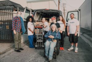 A diverse group of volunteers unloading a van for a charity event, showcasing teamwork and support.